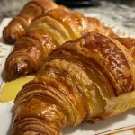 Close-up of golden-brown croissants filled with apples and cinnamon.