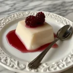 Close-up view of a creamy panna cotta topped with a berry sauce.