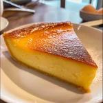 A side view of a golden-brown flan pâtissier with a smooth, glossy surface.