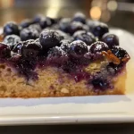 Close-up view of a blueberry yogurt cake with a moist texture and a golden crust.