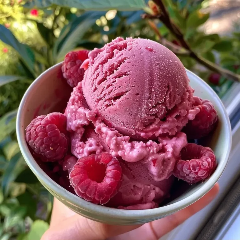 Close-up of a vibrant pink raspberry sorbet in a clear bowl, showing a creamy texture.